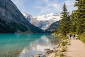 Visitors walking beside turquoise Lake Louise with the Canadian Rockies in Banff National Park