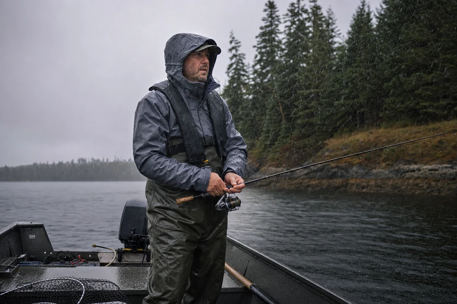 Canadian angler wearing a rain jacket, bibs and lifejacket while fishing in cold rain