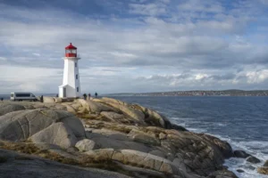 Peggys Point lighthouse on granite beside the Atlantic Ocean and a small tour van