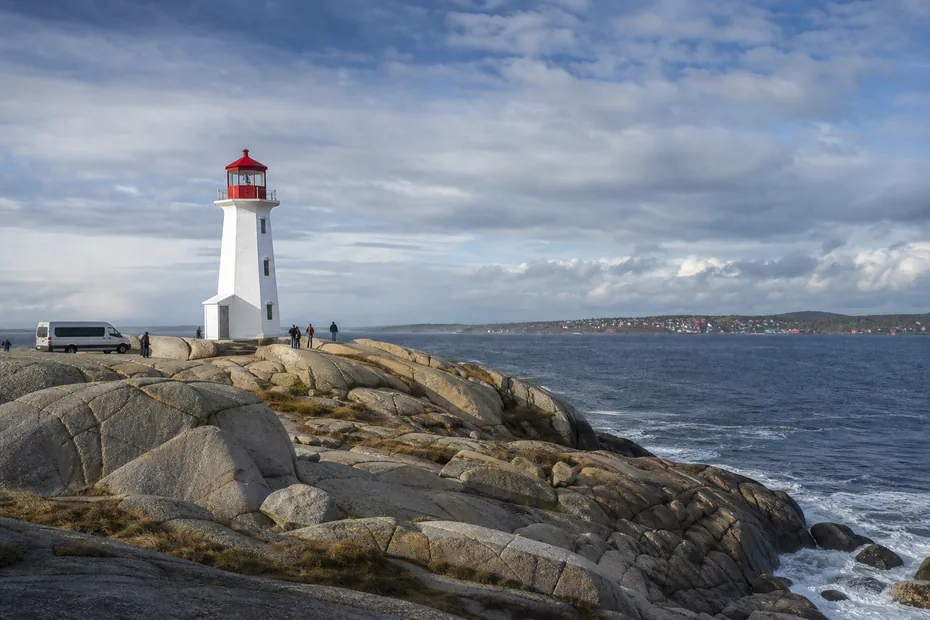 Peggys Point lighthouse on granite beside the Atlantic Ocean and a small tour van