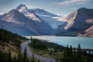 Tour minibus on the Icefields Parkway beside a turquoise lake and glacier in the Canadian Rockies