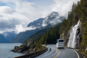 Tour coach on the Sea-to-Sky Highway beside Howe Sound and a waterfall on the way to Whistler